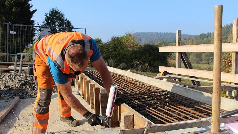 Polier Stefan Hegmann legt zum Abschluss der Bauarbeiten an der Wernarzer Brücke noch einmal Hand an.  Foto: Julia Raab       -  Polier Stefan Hegmann legt zum Abschluss der Bauarbeiten an der Wernarzer Brücke noch einmal Hand an.  Foto: Julia Raab