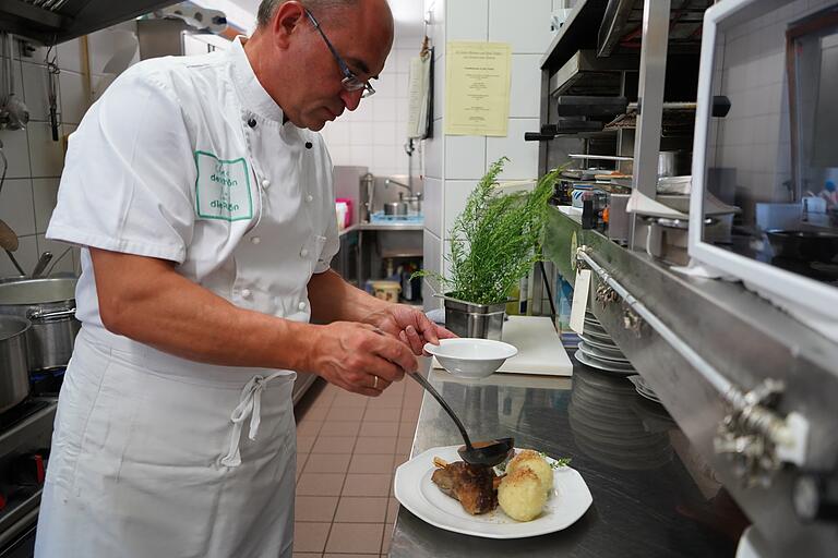 Claus Vorndran richtet einen Teller mit Lammhaxe vom Rhönschaf und Klößen an. Der Chef des Familienbetriebs Gasthaus und Brennerei Dickas in Bischofsheim ist erstmals bei den Rhönschaf-Genießerwochen dabei.