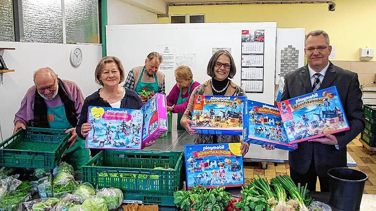 Adventskalender für Tafel-Kinder       -  (hh)  Die Sparda-Bank Nürnberg hat aus den Mitteln ihres Gewinn-Sparvereins 220 Playmobil-Adventskalender an die Schweinfurter Tafel gespendet. Mit ihrer nun schon zum zweiten Mal erfolgten Aktion will die Genossenschaftsbank in der Vorweihnachtszeit Kindern aus einkommensschwachen Familien eine Freude bereiten. Das erklärte der Filialleiter der Schweinfurter Filiale, Roland Kehrlein, bei der Übergabe der Kalender in der Tafel-Ausgabestelle am Bergl in Schweinfurt. Für die Tafel dankten Brigitte Salzer und Gertrud Morgenstern. Beide berichteten, dass bereits nachgefragt werde, ob es das Geschenk für Vier- bis Zehnjährige wieder gibt. Die Tafel gibt pro Woche an rund 700 bedürftige Familien noch gut erhaltenes, von Märkten und Bäckereien zur Verfügung gestelltes Essen aus. Dahinter stehen rund 2000 Betroffene, ein gutes Drittel davon sind Kinder und Jugendliche. Ein Teil der Kalender wird an die Tafel-Filiale in Gerolzhofen und an die Bürgerhilfe Schwebheim weitergereicht. Im Bild nehmen (von links) Salzer und Morgenstern die Kalender von Kehrlein entgegen. Außerdem dabei die Tafelmitarbeiter Waldemar Eller (links) sowie hinten Erich Müller und Sigrid Gehrsitz.