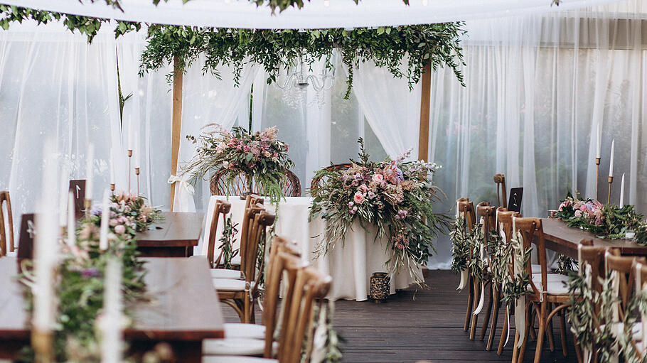 hochzeitszelt       -  Hochzeitszelt mit Holzmöbeln und Dekoration im Boho-Stil mit vielen Grünpflanzen und Blumengestecken.