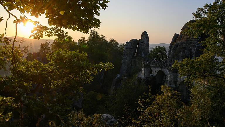 Sonnenaufgang über dem Nationalpark Sächsische Schweiz an der berühmten Basteibrücke.