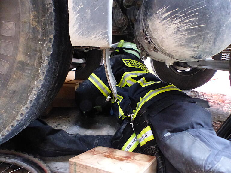 Ein Feuerwehrmann versucht mit Holzkeilen den Laster zu stabilisieren.