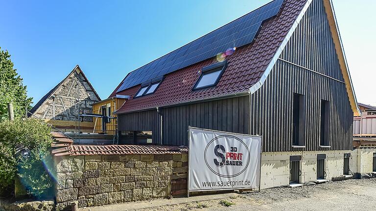 Hinter der grauen Holzverkleidung ist die Dämmung für das KfW 40+-Haus angebracht. Ein Teil der alten Scheunenmauer umrundet den neuen Innenhof.