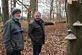 Waldbesitzer Elmar Kütt und Wolfgang Grimm vom Amt für Ernährung, Landwirtschaft und Forsten zeigen eine (tote) Buche, an deren Stamm der Pilz Zunderschwamm wächst. Die grüne Welle zeigt, der Vertragsnaturschutz den Baum als 'stehendes Totholz' fördert.