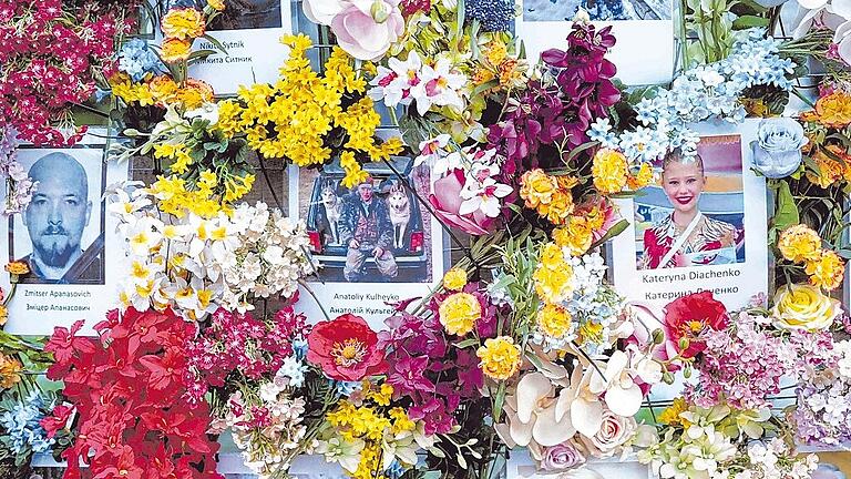 Reortage Ukraine       -  In Lwiw erinnern Fotos zwischen Kunstoffblumen an die Toten des Kriegs. Die westukrainische Stadt ist immer wieder Ziel von russischen Raketenangriffen. Viele Männer und Frauen dienen in der Armee.