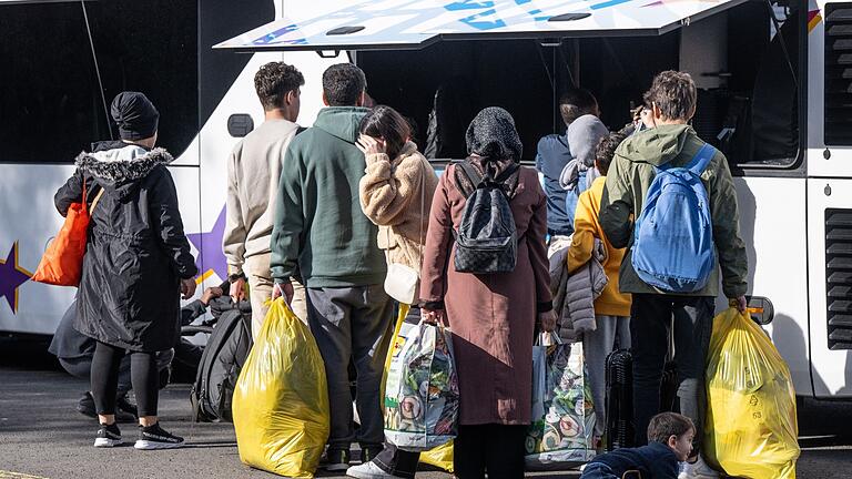 Flüchtlinge in Erstaufnahmeeinrichtung.jpeg       -  Flüchtlinge gehen in einer Erstaufnahmeeinrichtung zu einem wartenden Bus.