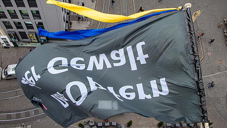 Am Grafeneckart des Würzburger Rathauses weht die Flagge für die Opfer aller Gewalt mit zwei Fahnenbändern in den ukrainischen Nationalfarben.