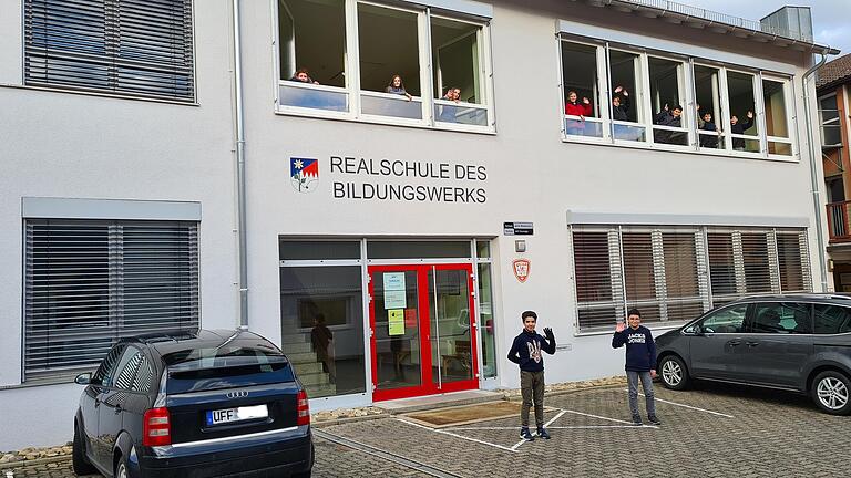 Die Realschule des Bildungswerks in Marktbreit. Im Bild winken Schülerinnen und Schüler aus den offenen Fenstern.