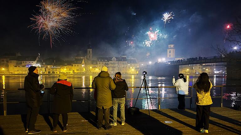 Menschen beobachten vom Stadtbalkon in Etwashausen aus das Feuerwerk über Kitzingen.