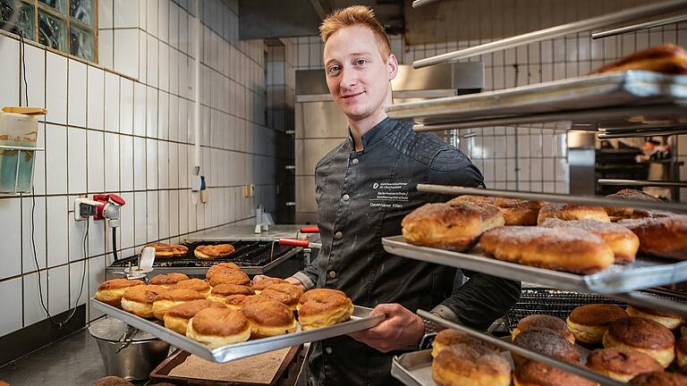 Chef des Dettelbacher Café Kehl: Kilian Dauenhauer steht mit einem Blech Krapfen in der Backstube.&nbsp;