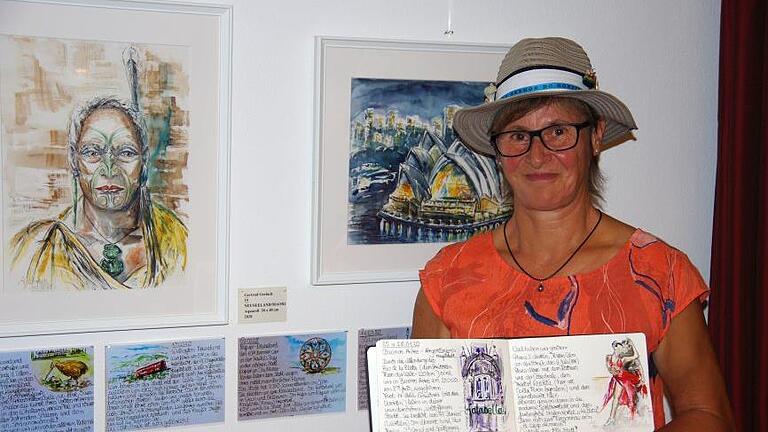 Gertrud Gerlach stellt aktuell 20 Aquarelle im Golfclub aus. Das Foto zeigt im Hintergrund eine Abbildung des Opernhauses von Sydney und das Bildnis eines Maori-Häuptlings, in der Hand hält sie ihr Skizzen-Tagebuch.  Fotos: Klaus Werner       -  Gertrud Gerlach stellt aktuell 20 Aquarelle im Golfclub aus. Das Foto zeigt im Hintergrund eine Abbildung des Opernhauses von Sydney und das Bildnis eines Maori-Häuptlings, in der Hand hält sie ihr Skizzen-Tagebuch.  Fotos: Klaus Werner