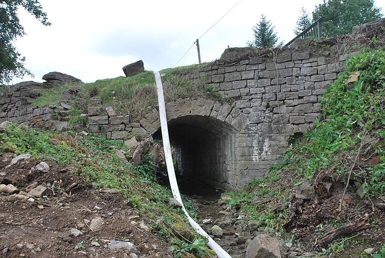 Die Bruchstein-Rundbogen-Brücke über dem Moosbach wird abgerissen.