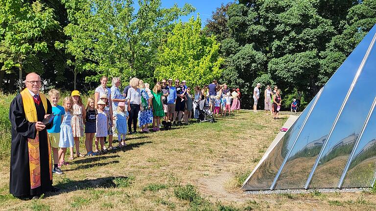 Prädikant Ulrich Betscher (links) mit Kindern und ihren Eltern an der Trinitatiskapelle.