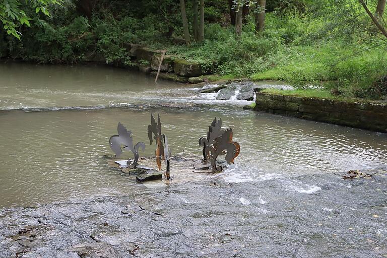 Der von Wasser durchflutete Wunschbrunnen im Streichwehr der Gollach ist ein Werk von Anna Lena Keller. Der von Wasser durchflutete Wunschbrunnen im Streichwehr der Gollach ist ein Werk von Anna Lena Keller.