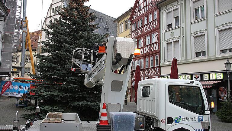 Der Weihnachtsbaum am Kitzinger Marktplatz steht. Die Lichterkette ist angebracht. Ein bisschen Weihnachtsstimmung in diesen trüben Tagen kann einziehen.