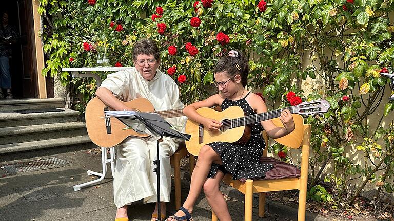 Claudia Annon spielt zum Abschluss der Segensfeier mit Leni Heinbuch Gitarre vor der Bücherei.       -  Claudia Annon spielt zum Abschluss der Segensfeier mit Leni Heinbuch Gitarre vor der Bücherei.