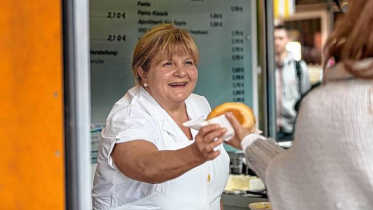 Die &bdquo;Mittlere&ldquo;, Silvia King, hinter der Theke ihres Bratwurststandes auf dem Marktplatz.