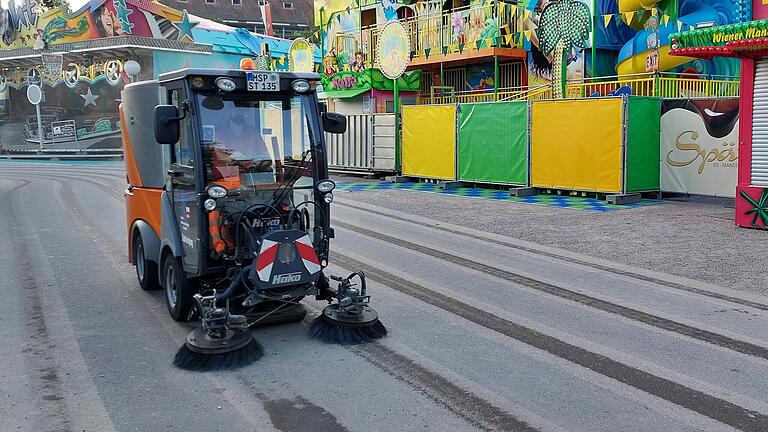 Eine Kehrmaschine sammelt Unrat auf dem Festplatz ein und reinigt den Asphalt.