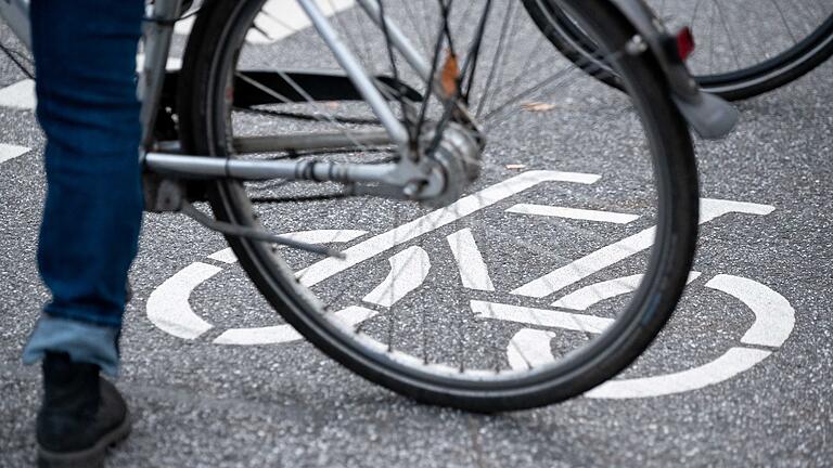 Fahrradfahrer       -  Ein Fahrrad-Symbol ist auf der Fahrbahn einer Straße hinter einem Fahrrad zu sehen.