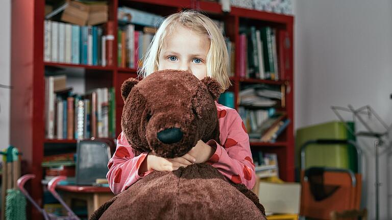 Ella steht mit ihrem Bären im Wohnzimmer. Die Dreijährige ist ein aufgewecktes Kind, doch sprechen kann sie noch kaum.