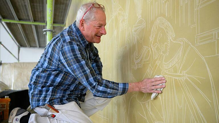 Restaurator Adrian Neus arbeitet am Wandbild 'Abendland' im Treppenhaus der Mozartareals in Würzburg.