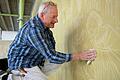 Restaurator Adrian Neus arbeitet am Wandbild 'Abendland' im Treppenhaus der Mozartareals in Würzburg.