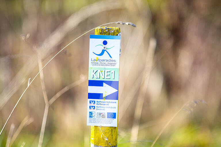 So sieht die typische Streckenkennzeichnung im Laufparadies Haßberge aus: Unter einem stilisierten Läufer befindet sich die Streckenkennzeichnung - hier KNE1 - und darunter der Richtungspfeil. So sieht die typische Streckenkennzeichnung im Laufparadies Haßberge aus: Unter einem stilisierten Läufer befindet sich die Streckenkennzeichnung - hier KNE1 - und darunter der Richtungspfeil. 
