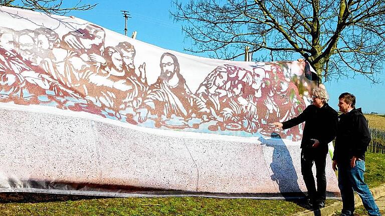 Leonardo Da Vincis berühmtes Wandgemälde &bdquo;Das letzte Abendmahl&ldquo; lieferte die Vorlage für das geplante Stahlobjekt an der Frickenhäuser Kapellensteige. Als Vorgeschmack hat Gestalter Michael Ehlers (links), im Bild zusammen mit dem Vorsitzenden des Winzervereins Wolfgang Betz seinen Entwurf maßstabsgerecht auf eine Plane übertragen.