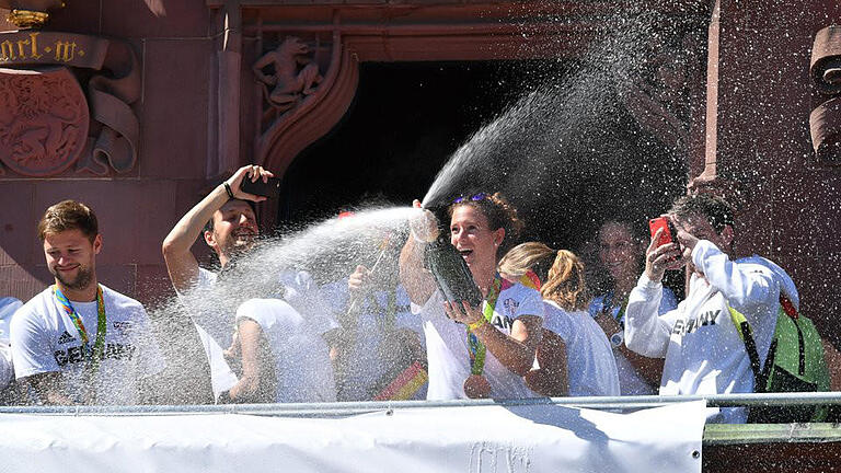 Feucht fröhlich       -  Hockeyspielerin Janne Müller-Wieland (M) versprüht vom Balkon aus einer Flasche Schaumwein. Foto: Arne Dedert