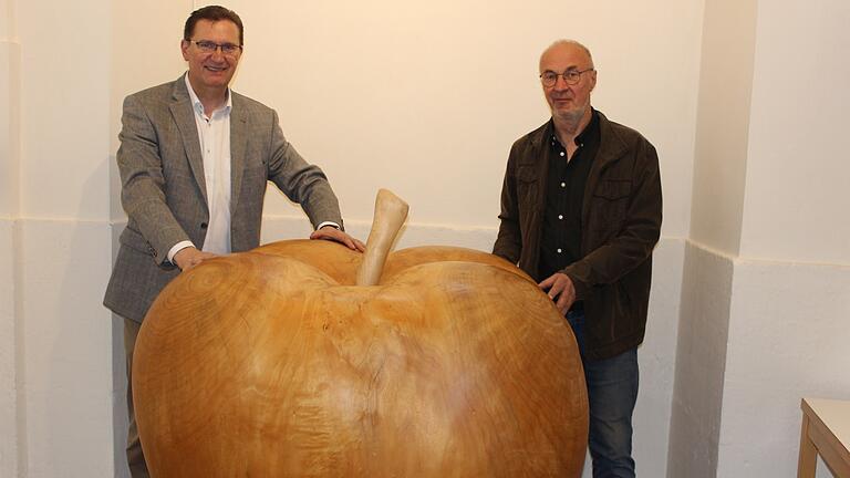 Ein riesengroßer Apfel, ein Werk des Bildhauers Herbert Holzheimer (rechts) schmückt zum 'Jahr des Apfels' die Kirche Mariä Himmelfahrt. Pfarrer Andreas Krefft stellte das Projekt 'Jahr des Apfels' vor.