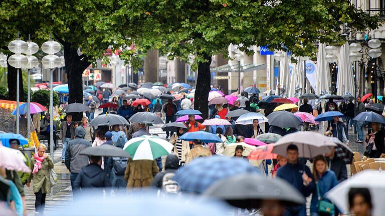 Menschen in Fußgängerzone       -  Passanten mit Regenschirmen laufen im Regen durch die Fußgängerzone Neuhauser Straße und Kaufingerstraße nahe dem Stachus in München.