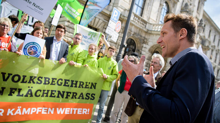 nterstüzer des Volksbegehren gegen Flächenfraß demonstrieren - 17.07.2018, Bayern, München: Ludwig Hartmann (r), Fraktionsvorsitzender von Bündnis 90/Die Grünen im Bayerischen Landtag, spricht vor den Unterstützern des Volksbegehrens gegen Flächenfraß in Bayern, die vor dem Justizpalast gegen das Urteil des Oberlandesgerichts, das das Volksbegehren als nicht zulässig erklärt hat, protestieren. Die Initiatoren des Volksbegehrens haben gegen die Nichtzulassung des Volksbegehrens durch das Innenministerium geklagt. Der Bayerischer Verfassungsgerichtshof hat in seinem Urteil nun gegen die Zulässigkeit des Volksbegehrens gegen Flächenfraß entschieden. Foto: Matthias Balk/dpa +++ dpa-Bildfunk +++ nterstüzer des Volksbegehren gegen Flächenfraß demonstrieren - 17.07.2018, Bayern, München: Ludwig Hartmann (r), Fraktionsvorsitzender von Bündnis 90/Die Grünen im Bayerischen Landtag, spricht vor den Unterstützern des Volksbegehrens gegen Flächenfraß in Bayern, die vor dem Justizpalast gegen das Urteil des Oberlandesgerichts, das das Volksbegehren als nicht zulässig erklärt hat, protestieren. Die Initiatoren des Volksbegehrens haben gegen die Nichtzulassung des Volksbegehrens durch das Innenministerium geklagt. Der Bayerischer Verfassungsgerichtshof hat in seinem Urteil nun gegen die Zulässigkeit des Volksbegehrens gegen Flächenfraß entschieden. Foto: Matthias Balk/dpa +++ dpa-Bildfunk +++