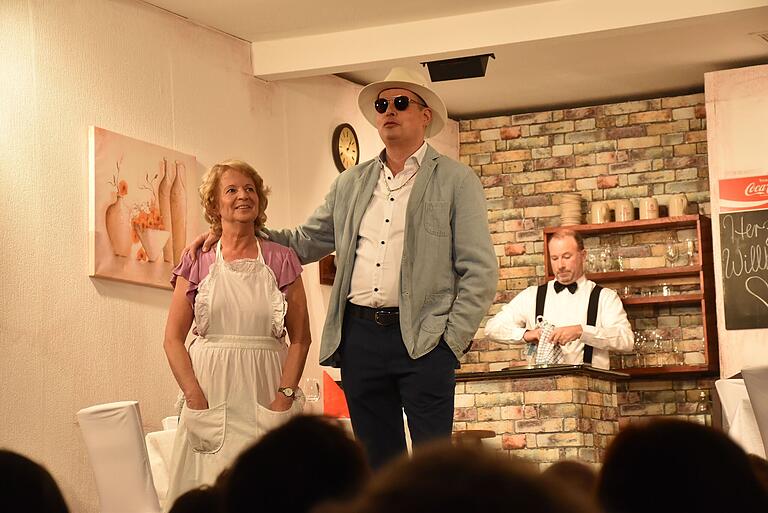 Der neureiche Cousin, Heinz von Pappenheim (Alexander Krack/Mitte) ist zur Visite eingekehrt. Wirtin Traudl (Irene Schmitt) und ihr Lebensgefährte Jan versuchen, alles zum Guten zu wenden. Der neureiche Cousin, Heinz von Pappenheim (Alexander Krack/Mitte) ist zur Visite eingekehrt. Wirtin Traudl (Irene Schmitt) und ihr Lebensgefährte Jan versuchen, alles zum Guten zu wenden.