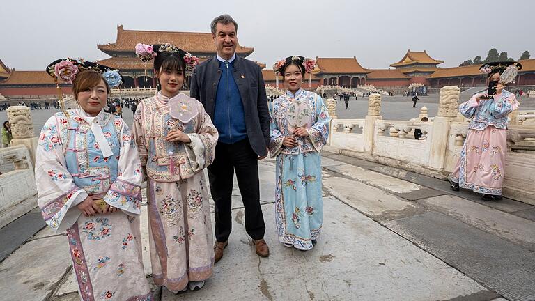 Bayerns Ministerpräsident Söder.jpeg       -  Markus Söder besucht die historische verbotene Stadt in der chinesischen Hauptstadt und steht neben Frauen in traditionellen Kostümen.