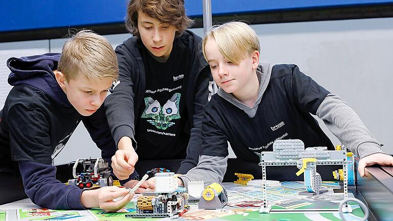 Valentin Steiner (links, 14), Paul Wohlfahrt (13) und Manuel Ewald (14, rechts) vom Team JSG Globes (Johann-Schöner-Gymnasium Karlstadt) basteln an ihrem Lego-Roboter für den Parcour.