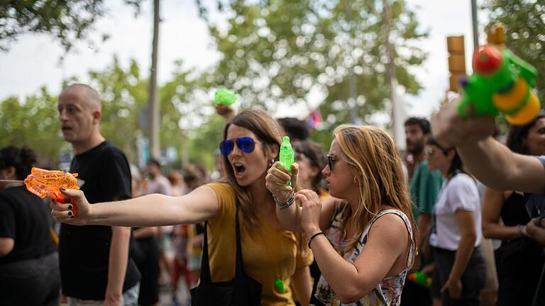 Demonstration gegen Massentourismus in Barcelona       -  Demonstrantinnen verpassen Urlaubern eine unerbetene Abkühlung aus Wasserpistolen.