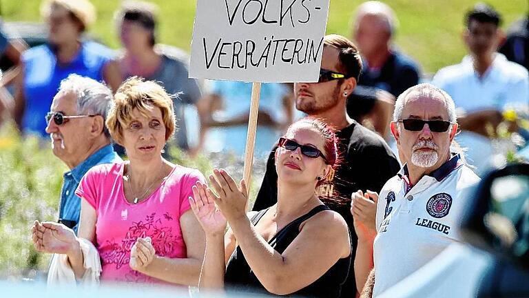 dpa-Story: Ein Jahr Flüchtlingskrise       -  Das Archivfoto vom August 2015 zeigt Proteste gegen Bundeskanzlerin Angela Merkel vor einer Flüchtlingsunterkunft in Heidenau.