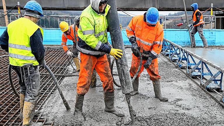 A3: Brückenguss in eisigem Wind       -  Hoch reckt die Betonpumpe ihren grünen Arm in kühnem Bogen in die Luft. Auf der einen Seite füllt ein Betonmischwagen seinen Inhalt in ihren Fülltrichter, auf der anderen Seite wandert das graue Gemisch durch einen dicken Schlauch genau dorthin, wo es gebraucht wird, zwischen die Bewehrungen aus Baustahl.