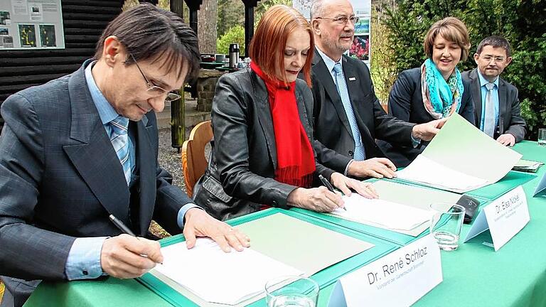 Vertragsunterzeichnung mitten im Wald. Die Unterschriften von (von links) Rene Schloz (Ganerbschaft), Elsa Nickel (Bundesumweltministerium) und Axel Kunze (Bundesanstalt für Immobilienaufgaben) besiegeln die Zukunft des ehemaligen US-Truppenübungsplatzes Brönnhof bei Schweinfurt als Nationales Naturerbe. Beobachter sind MdB Anja Weisgerber und Andreas Laudensack (Bayerisches Umweltministerium).