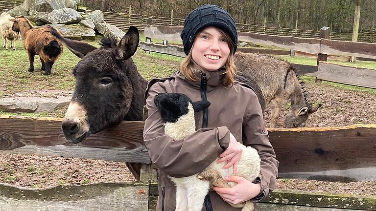 Samira Kempf aus Bad Bocklet ist im Park als Tierpflegerin beschäftigt. Das kleine Rhönschaf, das sie im Arm hält, hat noch keinen Namen. Für das Tier können Tierfreunde eine Patenschaft übernehmen.Foto: Charlotte Wittnebel-Schmitz       -  Samira Kempf aus Bad Bocklet ist im Park als Tierpflegerin beschäftigt. Das kleine Rhönschaf, das sie im Arm hält, hat noch keinen Namen. Für das Tier können Tierfreunde eine Patenschaft übernehmen.Foto: Charlotte Wittnebel-Schmitz