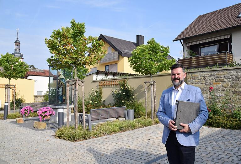 Am neuen Mutter Anna-Platz weist Geldersheims Bürgermeister Oliver Brust nach dem Abriss eines alten Gehöfts auf die gelungene Gestaltung plus Parkflächen hin. Am neuen Mutter Anna-Platz weist Geldersheims Bürgermeister Oliver Brust nach dem Abriss eines alten Gehöfts auf die gelungene Gestaltung plus Parkflächen hin.