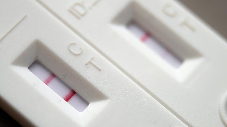 Ein positiver Corona-Schnelltest liegt auf einem Tisch neben einem Corona-Schnelltest, der schwach eine positive Linie hat. Die Corona-Zahlen steigen auch in Rhön-Grabfeld seit mehreren Tagen kontinuierlich an.