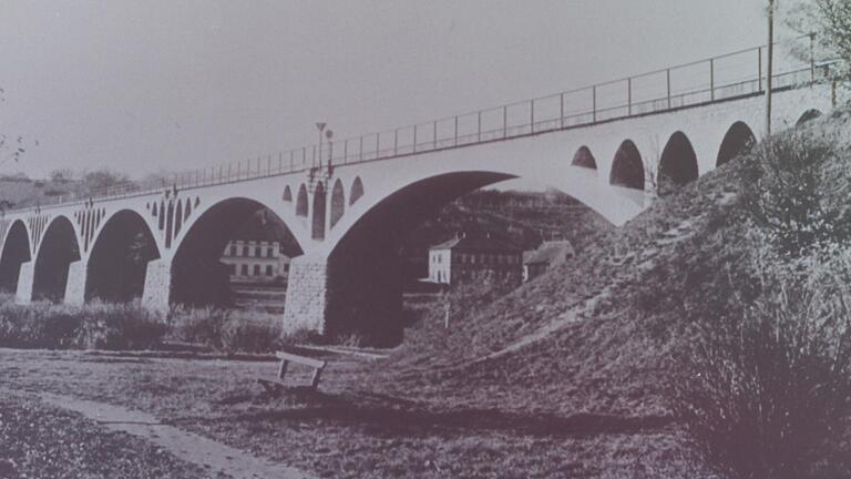 4.4.1945: Sprengung der Kitzinger Mainbrücken durch deutsche Pinoniere. Die in Bruchstein gemauerte einspurige Gerolzhöfer Eisenbahnbrücke prägte mit ihren gotisch anmutenden Bogen die Landschaft am Main. Das Bild entstand in den 1920er-Jahren. Rudolf Joachim