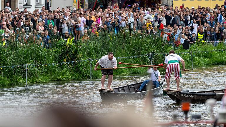 Die Zuschauerinnen und Zuschauer beobachten vom trockenen Ufer aus den Kampf auf dem Wasser.