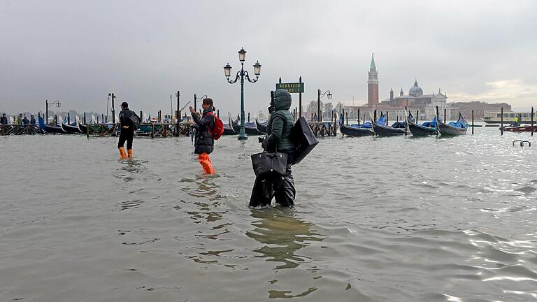 Menschen waten über einen überfluteten Platz in Venedig. Die Flut erreichte am späten Dienstag einen Höchststand von 187 cm.&nbsp;