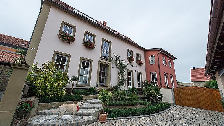 Haus Olerink mit Vorplatz und Anbau. Der fränkische Stil blieb auch nach der Sanierung und Dämmung des alten Sandstein-Bauernhauses des Ehepaars Olerink erhalten. Das nach hinten versetzte Hoftor ermöglicht einen neuen Vorplatz. Das rote Dach, das darüber sichtbar ist, gehört zur Scheune, in die sich das Ehepaar Pfister eine Wohnung baute.