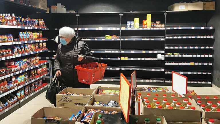 Eine Frau steht am 28. Februar in einem Supermarkt in Lwiw vor teilweise leeren Regalen. Vornehmlich lagerfähige Lebensmittel waren ausverkauft.