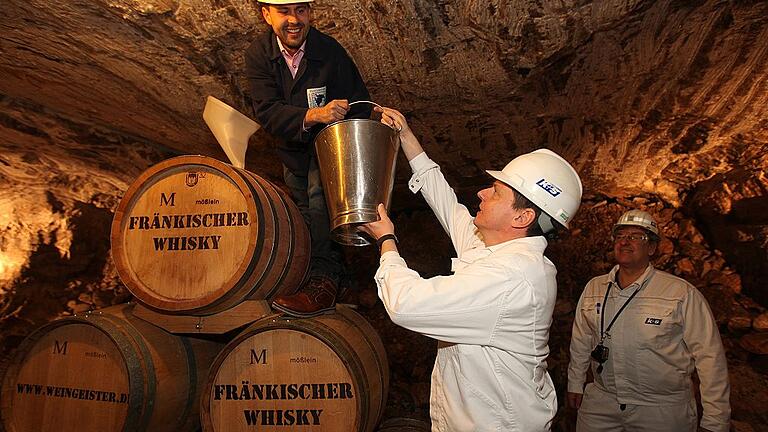 Fass abfüllen 600 Meter unter der Erdoberfläche: Thorsten Boeckers, Finanzvorstand des K+S-Konzerns, reicht Martin Mößlein einen Eimer mit dem Rohbrand des Whiskys, der nun im Erlebnis-Bergwerk Merkers für mindestens drei Jahre reifen soll. Karl-Heinz Heinemann beobachtet die Aktion. Fass abfüllen 600 Meter unter der Erdoberfläche: Thorsten Boeckers, Finanzvorstand des K+S-Konzerns, reicht Martin Mößlein einen Eimer mit dem Rohbrand des Whiskys, der nun im Erlebnis-Bergwerk Merkers für mindestens drei Jahre reifen soll. Karl-Heinz Heinemann beobachtet die Aktion.
