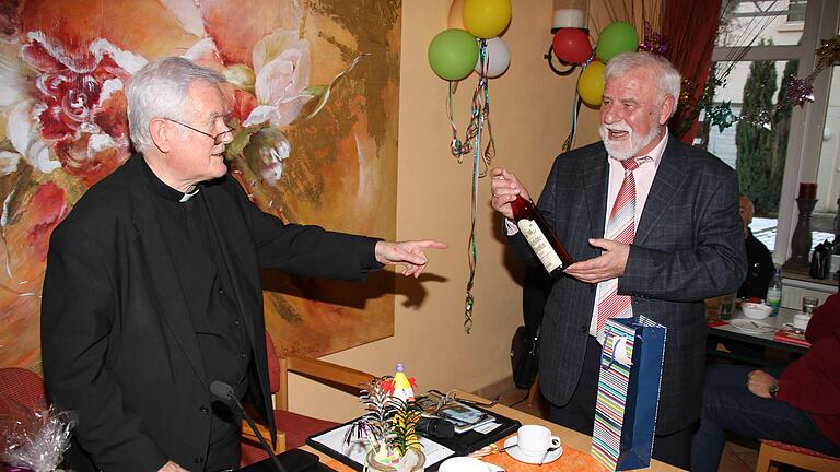 Eine Flasche 'Mürschter Tropfen' überreichte Erzählcafé-Organisator Eugen Albert (rechts) dem emeritierten Würzburger Bischof Friedhelm Hofmann. Natürlich bekam er auch die obligatorische Tasse. Foto: Dieter Britz       -  Eine Flasche 'Mürschter Tropfen' überreichte Erzählcafé-Organisator Eugen Albert (rechts) dem emeritierten Würzburger Bischof Friedhelm Hofmann. Natürlich bekam er auch die obligatorische Tasse. Foto: Dieter Britz