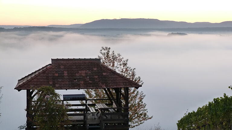 'Wenn Nebelschwaden wabern'. Eine Warnung vor szenischen Einstiegen. 
Dieses Leserfoto aus dem Oktober 2018 aus dem Archiv, hier ob des Nebels als Symbolbild eingesetzt, zeigt 'Die Weinhalla' in der Weinlage Sulzfelder Maustal über dem in Nebel verhüllten Maintal. Im Hintergrund der Schwanberg.